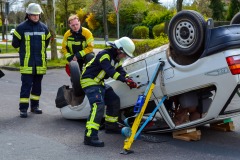 Arbeiten an einem auf dem Dach liegenden Auto.
