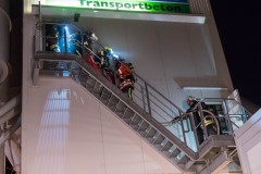 Eine verletzte Person, dargestellt durch eine Übungspuppe, wird aus dem Obergeschoss des Mischturms gerettet.