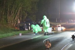 Feuerwehrleute in Chemikalienschutzanzüge reinigen die Fahrbahn.