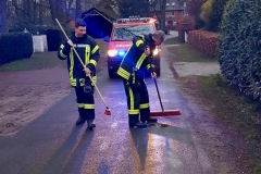 Einsatzkräfte der Feuerwehr bringen Ölbindemittel auf die Straße aus, um das Öl zu binden.