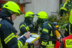 Einsatzkräfte unter Atemschutz bereiten sich für die Menschenrettung aus dem Gebäude vor.