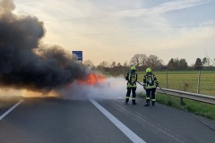Einsatzkräfte löschen den in Vollbrand stehenden PKW.