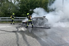 Einsatzkräfte löschen den in Vollbrand stehenden PKW.