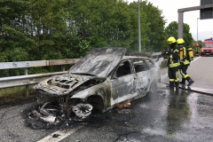 Einsatzkräfte löschen den in Vollbrand stehenden PKW.