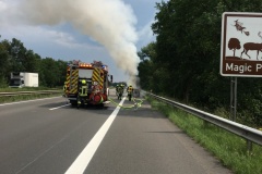 Einsatzkräfte löschen den in Vollbrand stehenden PKW.