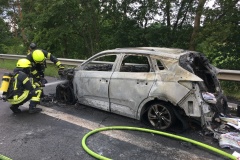 Einsatzkräfte löschen den in Vollbrand stehenden PKW.