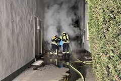 Löscharbeiten am brennenden PKW zwischen den Wohnhäusern.