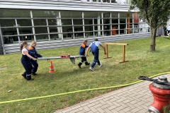 Transport von Wasserbechern mittels Trage durch einen Parcours. 
