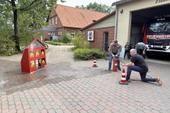 Die beiden Förderverein Vorsitzenden demonstrieren das Löschhaus den Kindern und Betreuer der Kinderfeuerwehr.