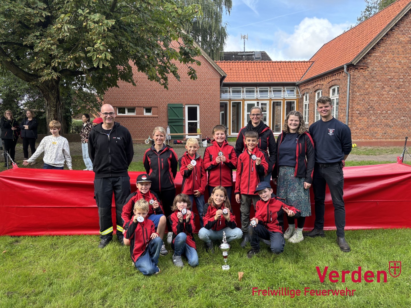 Die Kinderfeuerwehr Walle mit dem Wanderpokal und dem stellvertretenden Stadtbrandmeister Torben Voigt (links) sowie Stadtkinderfeuerwehrwart Cedric Schwarze (rechts).